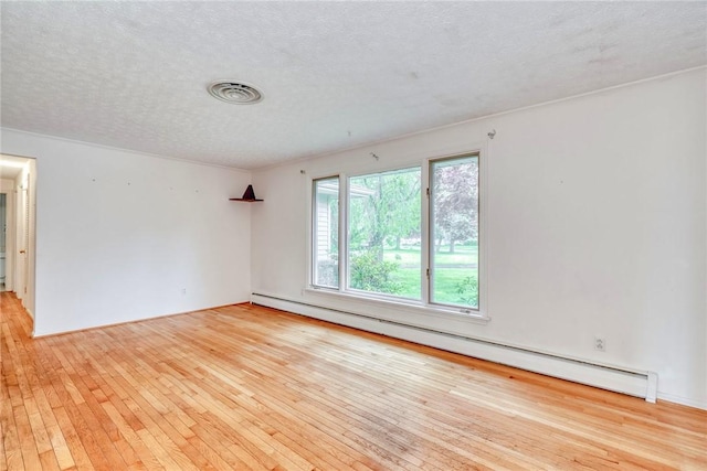 spare room with a baseboard radiator, hardwood / wood-style floors, and a textured ceiling