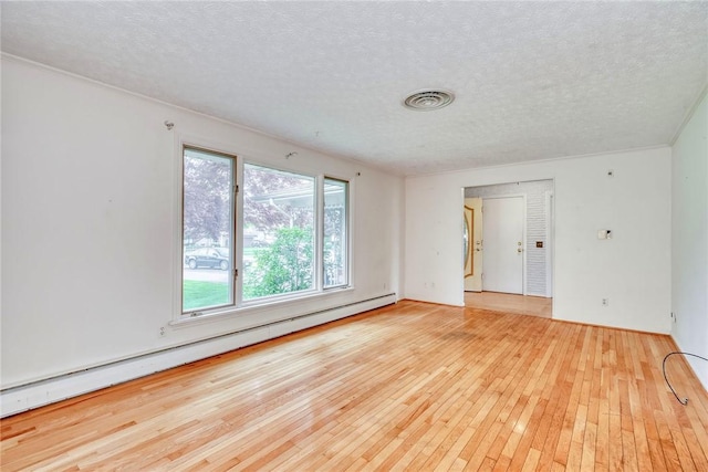 spare room with a baseboard heating unit, hardwood / wood-style floors, and a textured ceiling