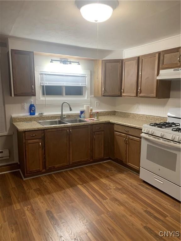 kitchen with gas range gas stove, under cabinet range hood, a sink, dark wood finished floors, and light countertops
