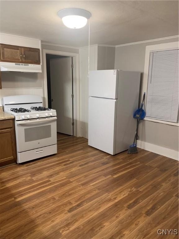 kitchen featuring white appliances, under cabinet range hood, ornamental molding, dark wood finished floors, and light countertops