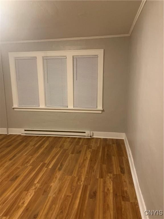 unfurnished room with a baseboard heating unit, crown molding, wood finished floors, and baseboards