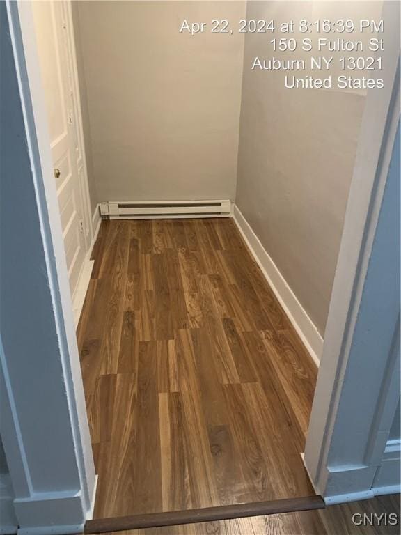hallway with a baseboard radiator, wood finished floors, and baseboards