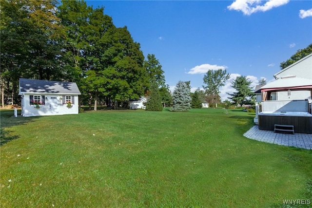 view of green lawn with a hot tub and an outdoor structure