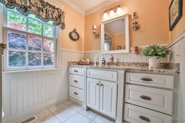 bathroom with tile patterned floors, vanity, a wainscoted wall, plenty of natural light, and crown molding
