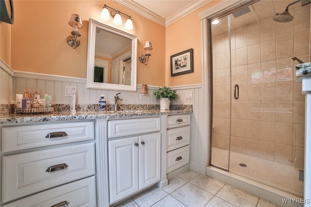 bathroom with a stall shower, ornamental molding, vanity, a wainscoted wall, and tile patterned flooring