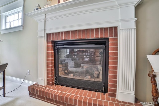 detailed view of a brick fireplace, carpet flooring, and baseboards