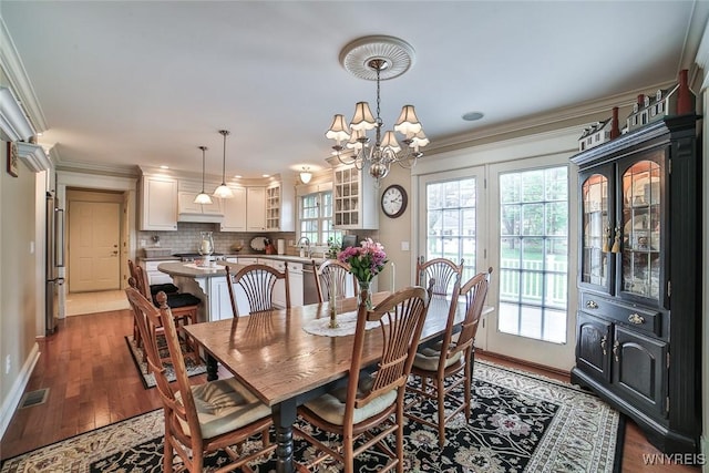 dining area featuring wood finished floors, a chandelier, crown molding, and baseboards