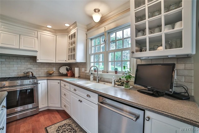 kitchen featuring appliances with stainless steel finishes, white cabinets, a sink, tasteful backsplash, and recessed lighting