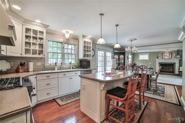 kitchen with white cabinetry, ornamental molding, wood finished floors, a breakfast bar, and decorative backsplash