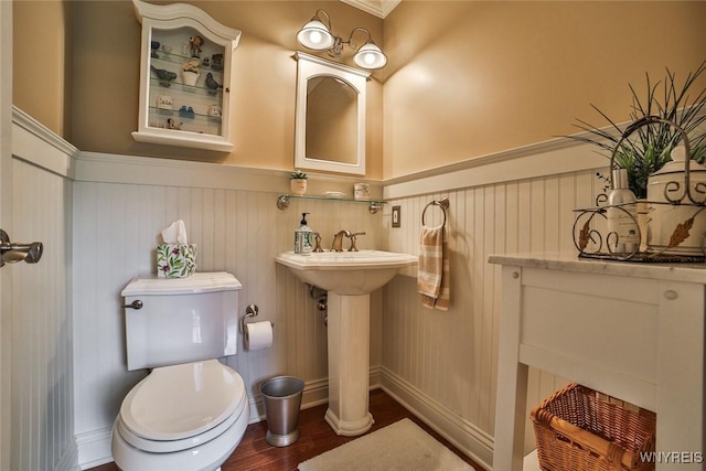 bathroom featuring a wainscoted wall, wood finished floors, and toilet