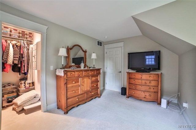 bedroom with light colored carpet, a closet, a walk in closet, and vaulted ceiling