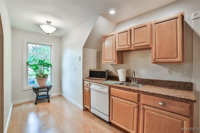 kitchen featuring white dishwasher, a sink, stainless steel microwave, light wood finished floors, and dark countertops