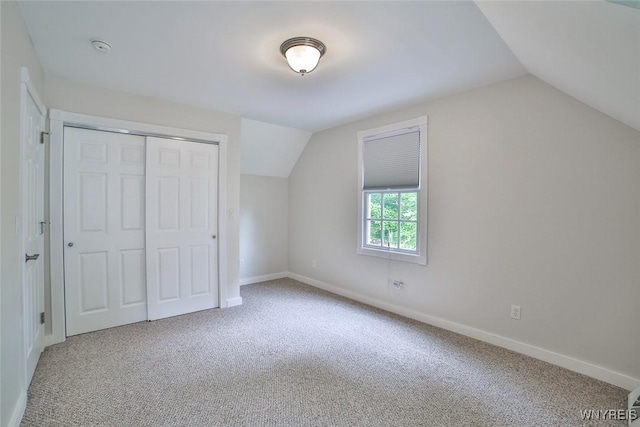 unfurnished bedroom with vaulted ceiling, carpet floors, a closet, and baseboards