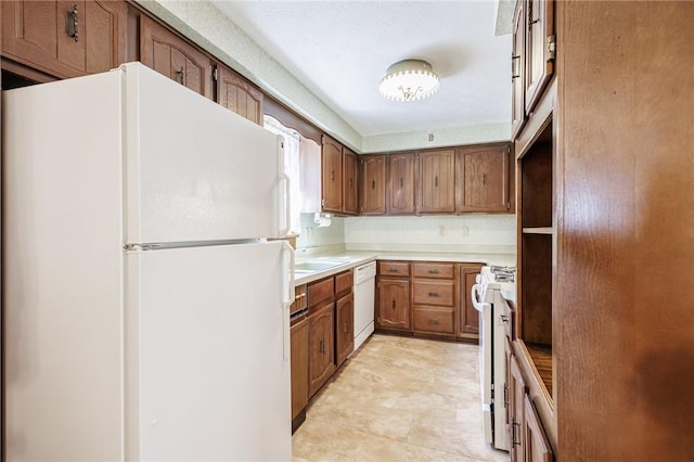 89 Chapel St, Mount Morris, NY 14510 - kitchen with white appliances, light countertops, brown cabinets, and a sink
