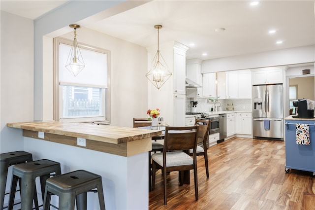 164 Elm Dr, Rochester, NY 14609 - kitchen with stainless steel appliances, white cabinetry, tasteful backsplash, a breakfast bar area, and decorative light fixtures