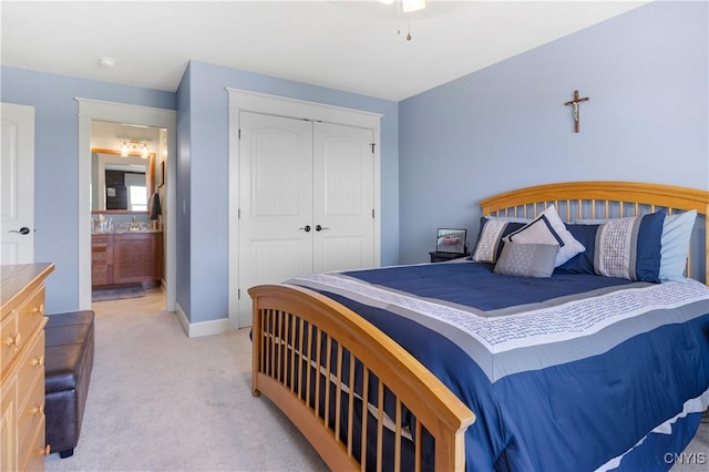 bedroom with light carpet, a closet, baseboards, and connected bathroom