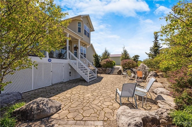 back of property featuring stairs, a patio, and a porch