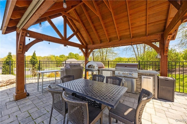 view of patio featuring area for grilling, a grill, fence, and outdoor dining space