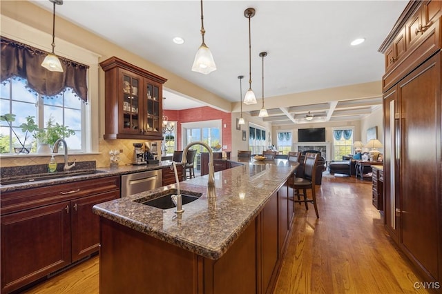 kitchen featuring a sink, open floor plan, coffered ceiling, plenty of natural light, and a fireplace