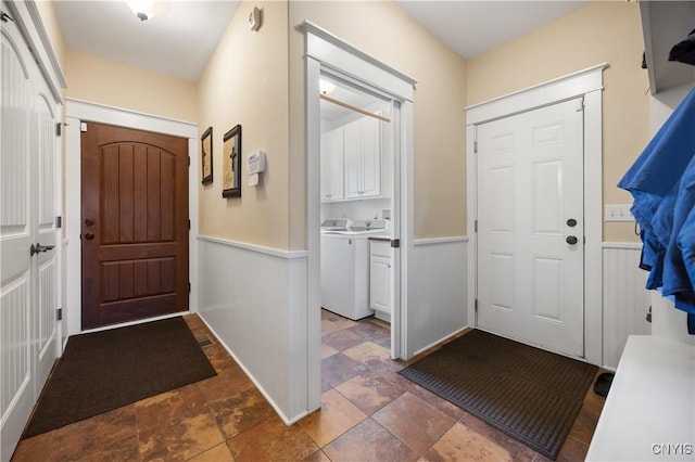 entryway featuring washer / dryer, a wainscoted wall, and dark stone finish flooring