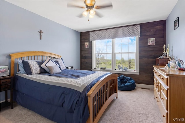 bedroom featuring light colored carpet, wood walls, and ceiling fan