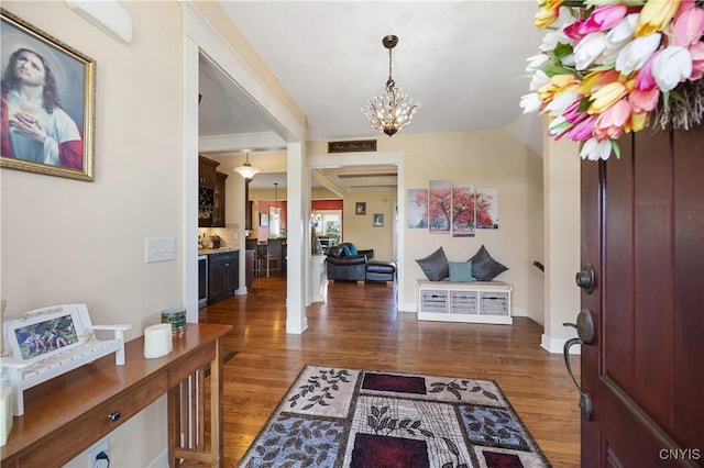 foyer featuring a chandelier, wood finished floors, lofted ceiling, and baseboards