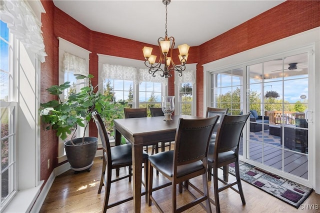 dining area with light wood-type flooring, a chandelier, and wallpapered walls