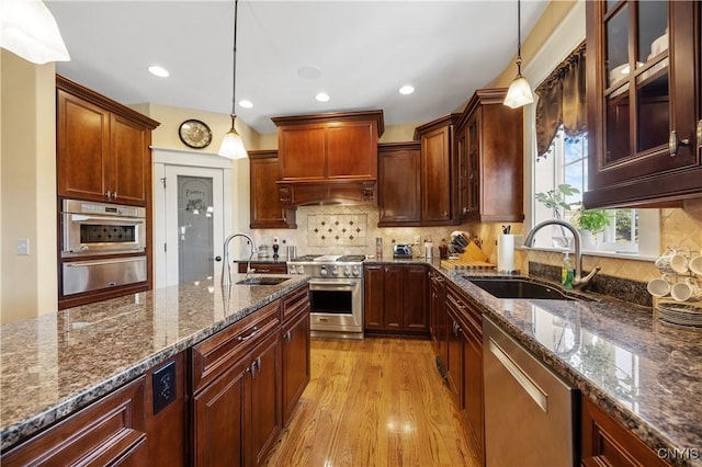 kitchen featuring stainless steel appliances, a sink, a warming drawer, light wood-style flooring, and recessed lighting