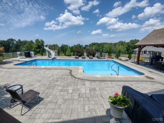 view of swimming pool featuring a water slide, fence, a patio area, and a gazebo