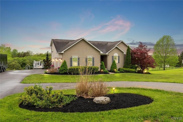 view of front of home with curved driveway and a front yard