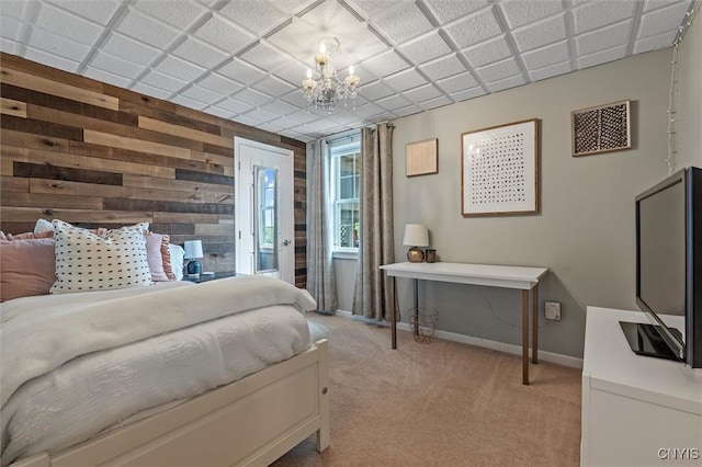 bedroom featuring wood walls, light colored carpet, access to outside, a chandelier, and baseboards