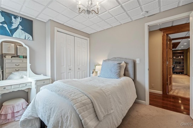 carpeted bedroom featuring a closet, a chandelier, and baseboards