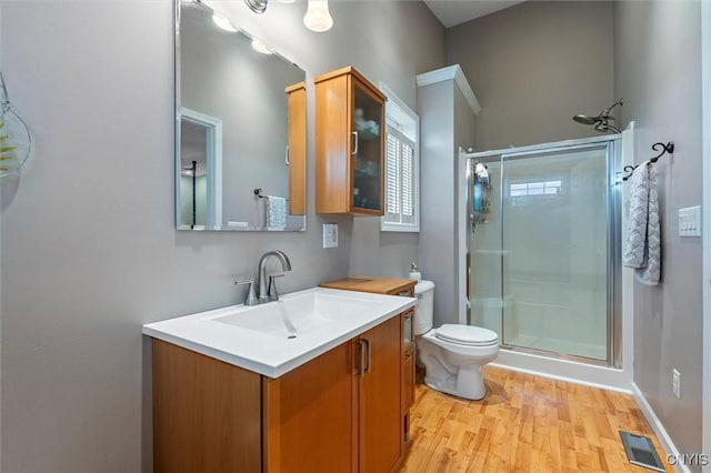 full bathroom with a stall shower, wood finished floors, vanity, and toilet