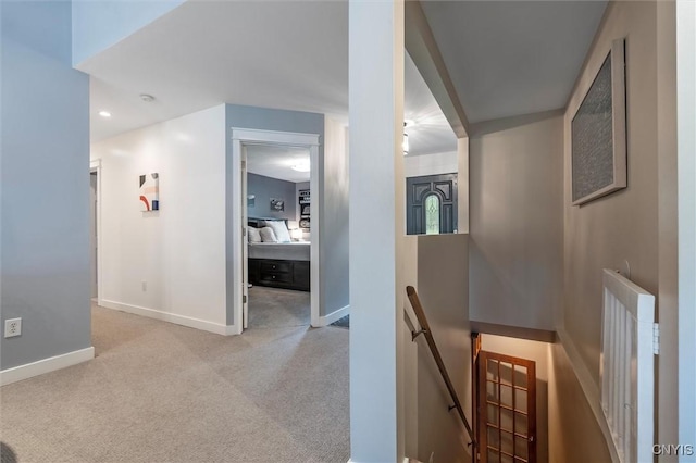 hall featuring an upstairs landing, baseboards, and carpet flooring