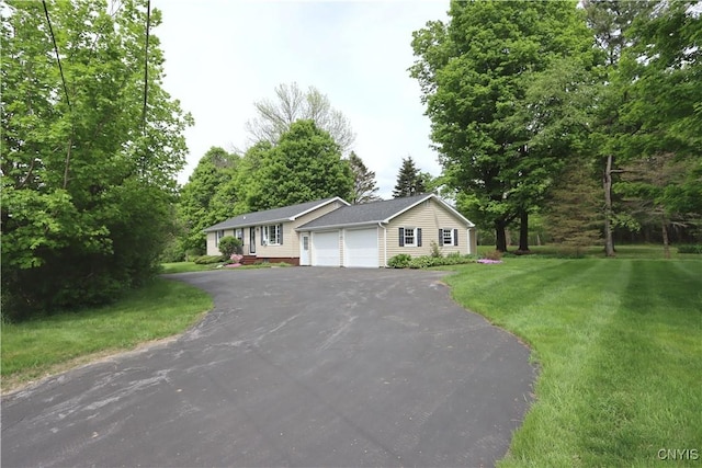 ranch-style home with driveway, an attached garage, and a front yard