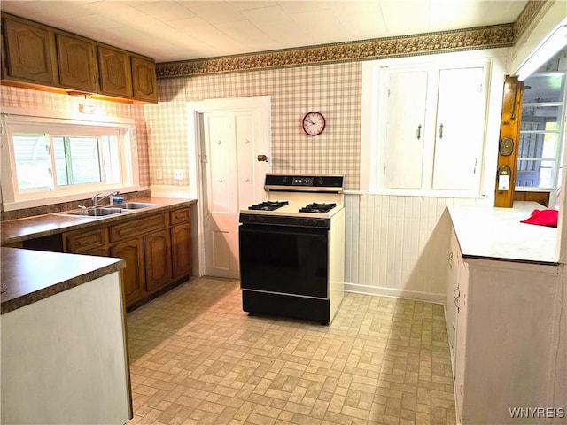 2282 Rte 305, Clarksville, NY 14727 - kitchen with gas range, a sink, brick patterned floors, brown cabinets, and wallpapered walls
