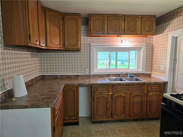 2282 Rte 305, Clarksville, NY 14727 - kitchen featuring wallpapered walls, gas range oven, a sink, brown cabinets, and dark countertops