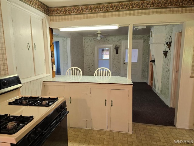 2282 Rte 305, Clarksville, NY 14727 - kitchen featuring white range with gas stovetop, wallpapered walls, a ceiling fan, light countertops, and white cabinets