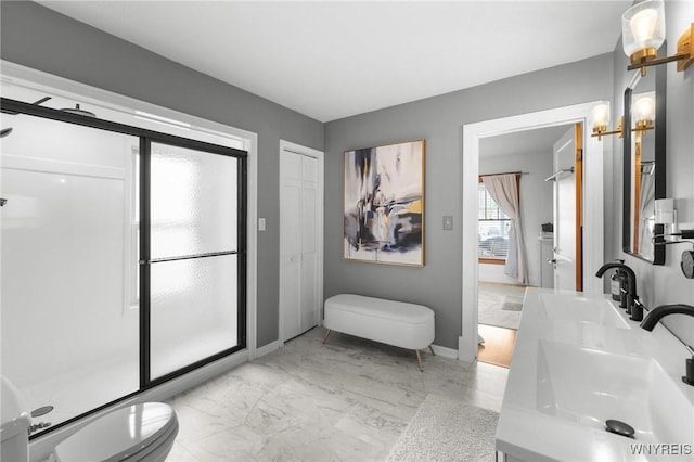 bathroom featuring marble finish flooring, toilet, double vanity, and baseboards