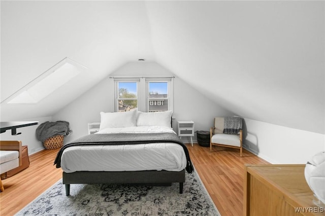 bedroom featuring a skylight, vaulted ceiling, and wood finished floors