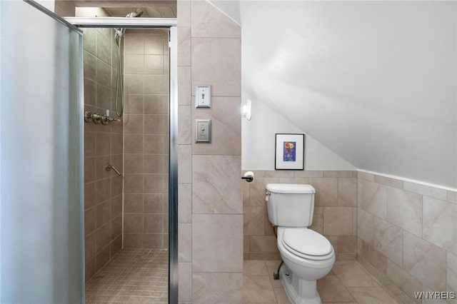 full bathroom featuring a shower stall, tile walls, toilet, tile patterned floors, and vaulted ceiling