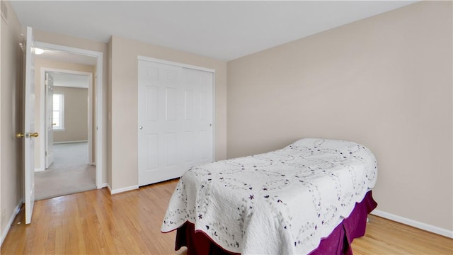 bedroom with light wood finished floors, baseboards, and a closet