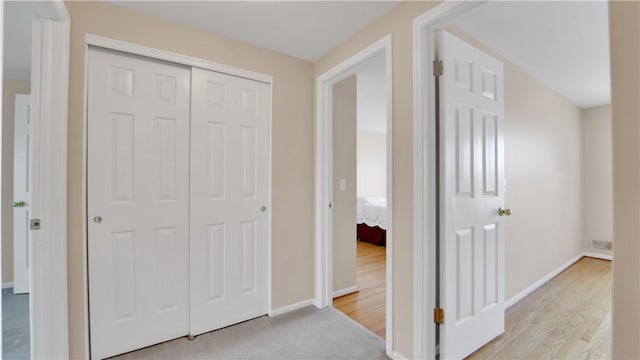 hallway featuring baseboards and light wood-type flooring