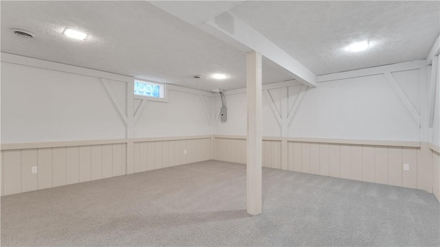 below grade area with carpet flooring and a wainscoted wall