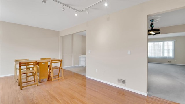 dining area featuring rail lighting, baseboards, and wood finished floors