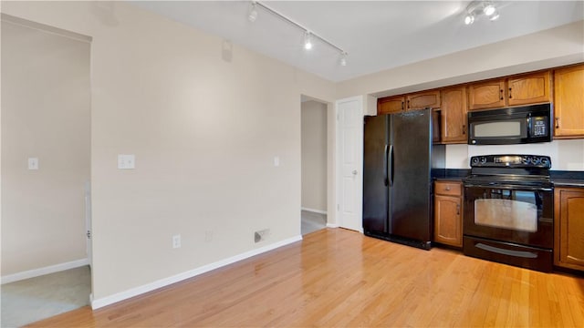kitchen featuring black appliances, dark countertops, brown cabinets, and baseboards