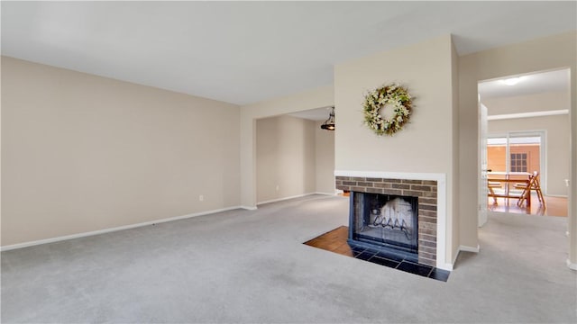 unfurnished living room featuring carpet flooring, a brick fireplace, and baseboards