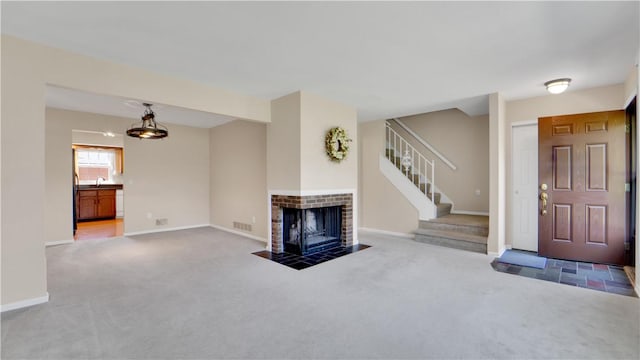 unfurnished living room with carpet flooring, stairs, a tile fireplace, and baseboards