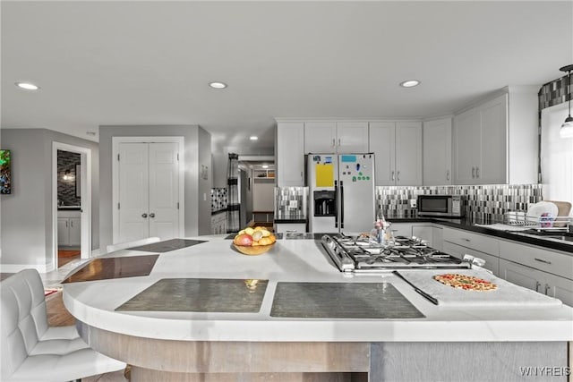 kitchen with appliances with stainless steel finishes, a kitchen island, backsplash, recessed lighting, and white cabinetry