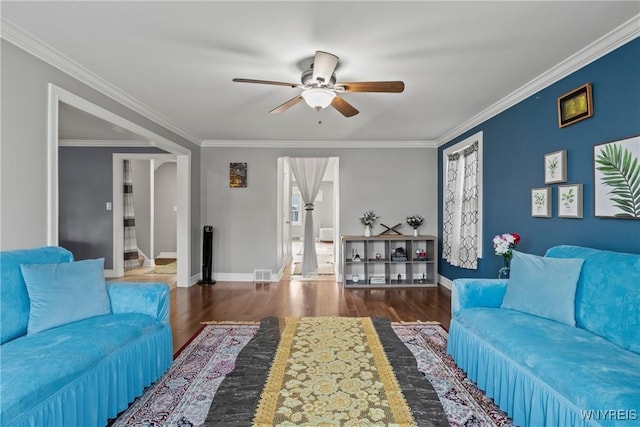 living room featuring ceiling fan, wood finished floors, baseboards, and crown molding